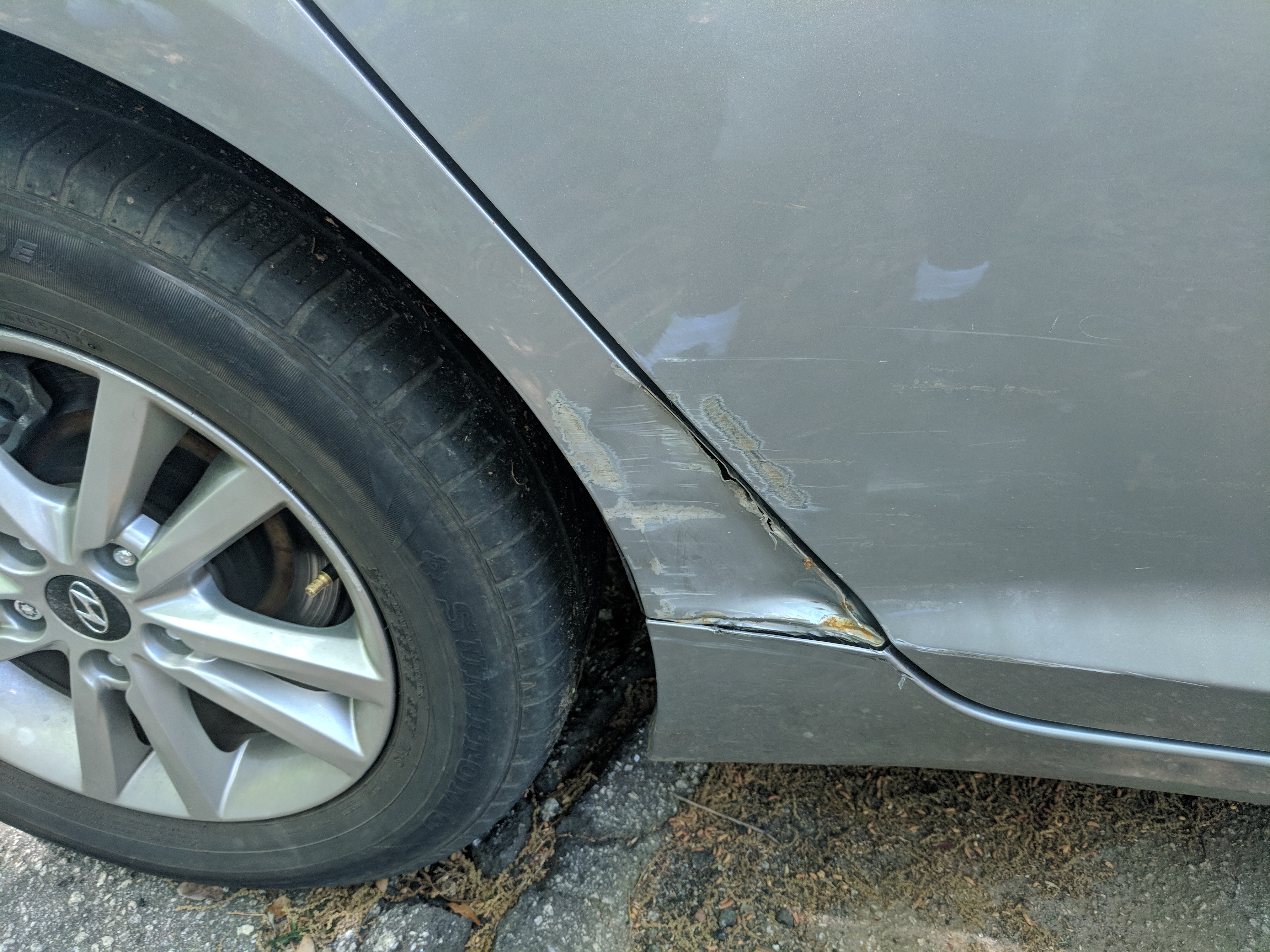 Close-up of a long scratch and crease along a car door