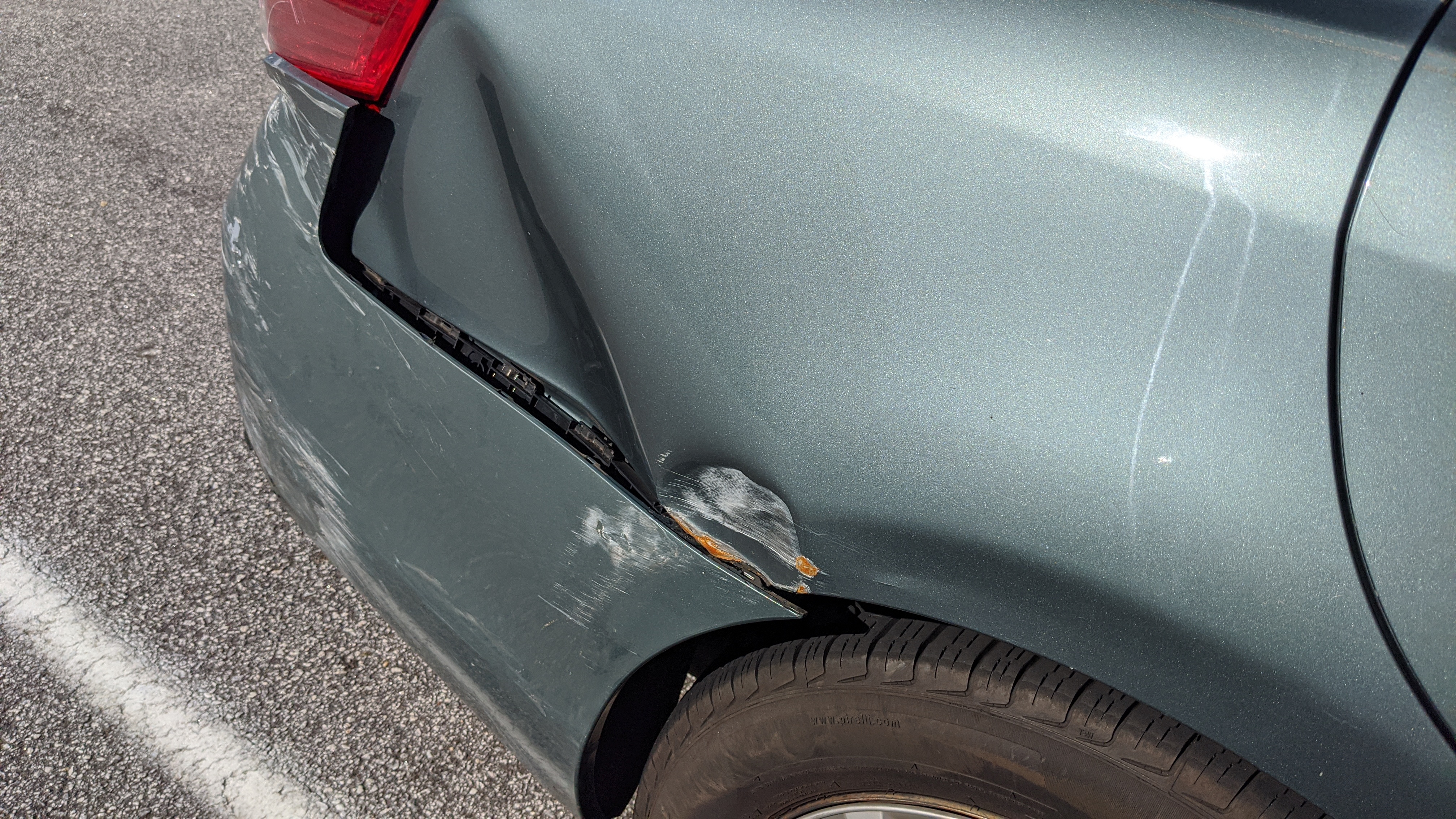Rear bumper dent and scuff damage on a sedan
