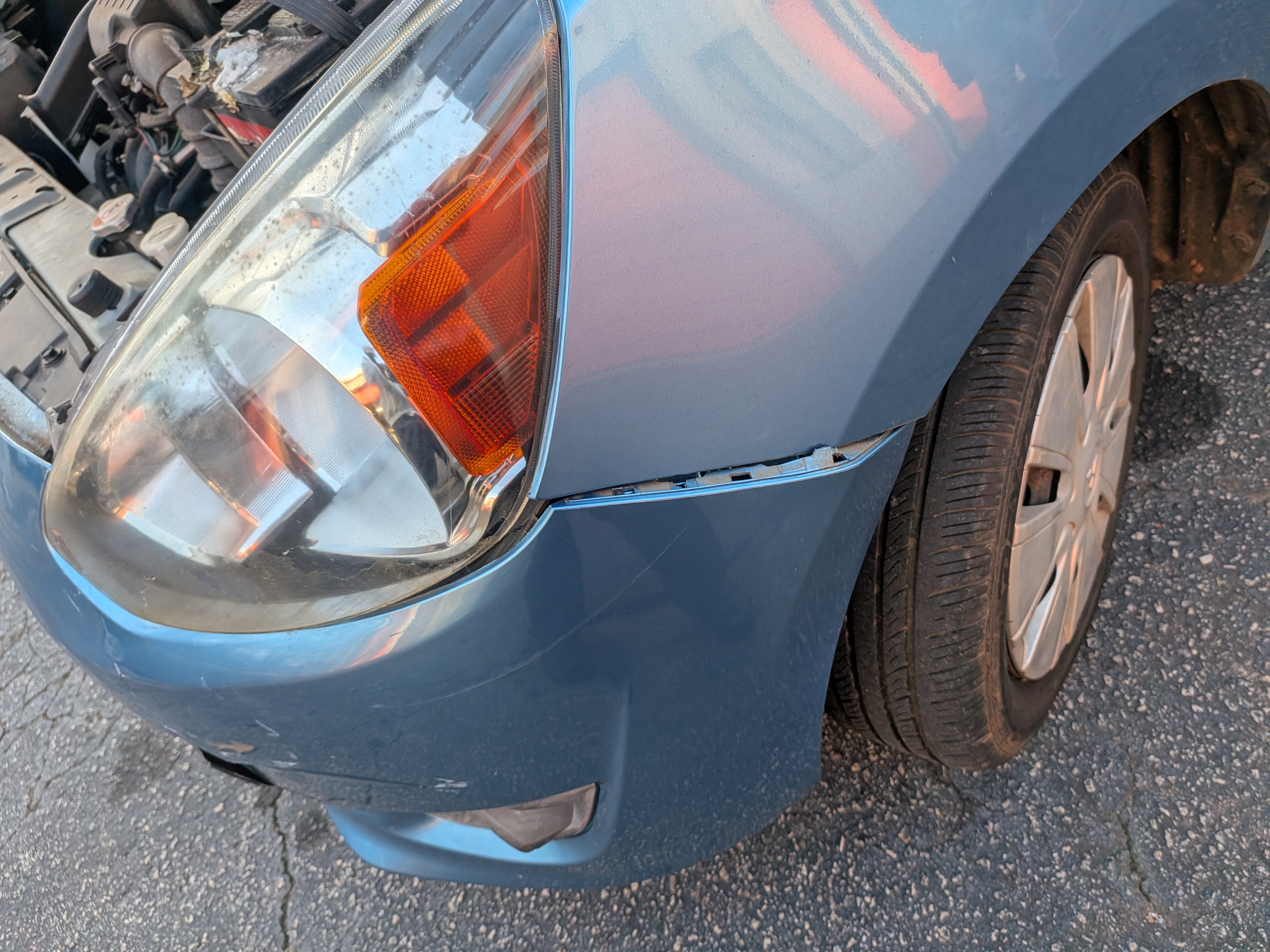 Blue sedan front fender and bumper damage with hood open, in for repair estimate