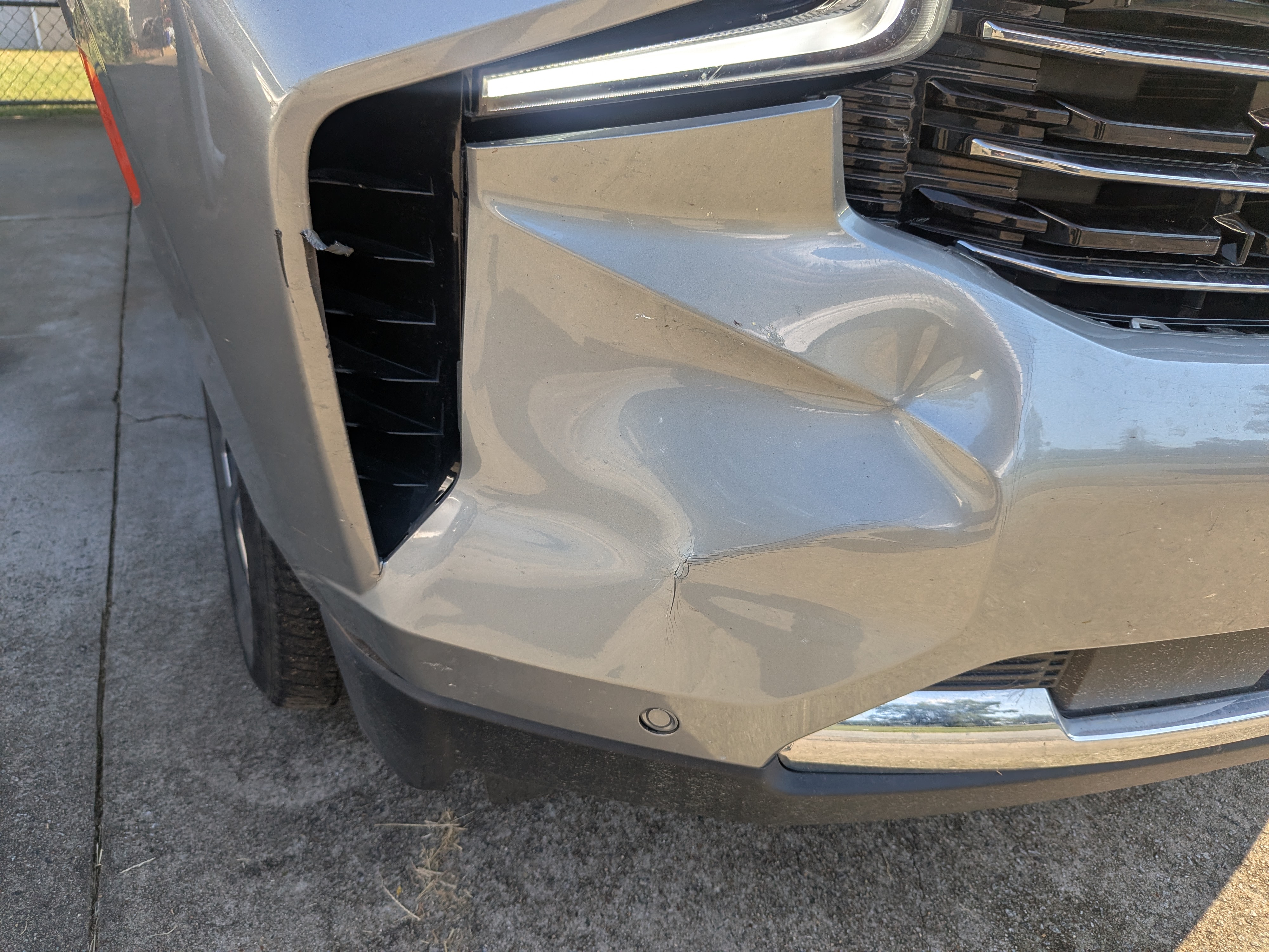 Silver truck front bumper with dent and cracked paint damage